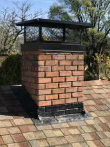 masonry chimney with black flashing and black chimney cap