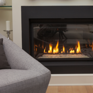 a lit gas fireplace insert with a gray chair near it